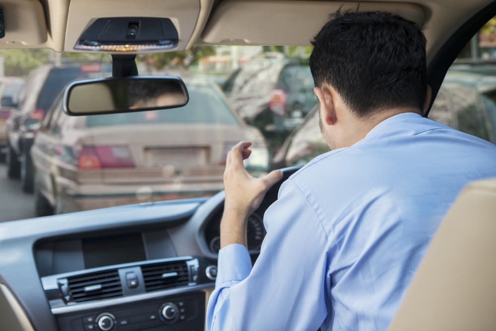 Rear view of furious young man driving a car on the road at the traffic jam