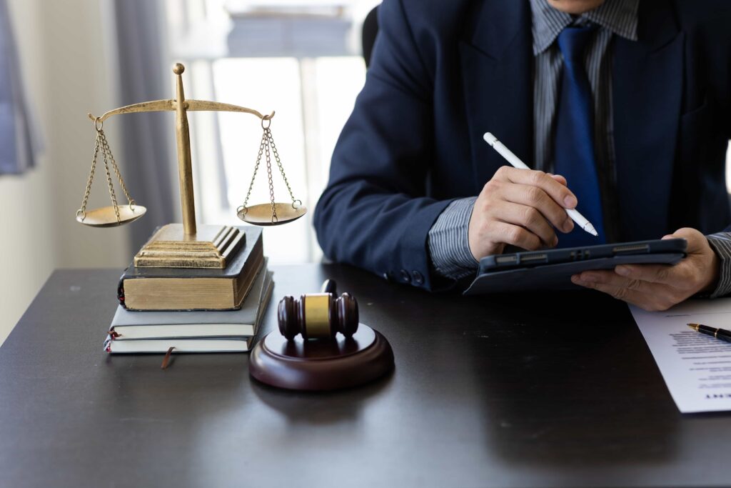 Lawyer working at desk with justice scales, gavel, and legal documents.