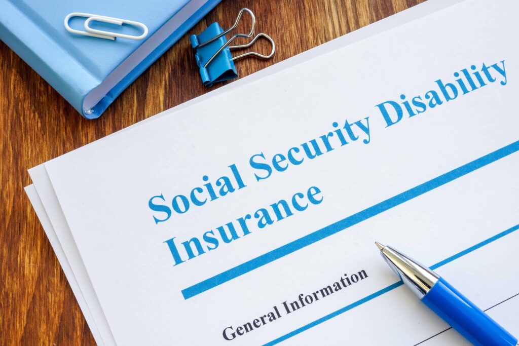 Social Security Disability Insurance documents on a desk with a pen and binder.