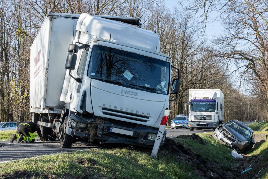 Commercial truck accident with a large box truck off the roadway and a damaged car in a ditch, showing serious collision impact. Commercial truck accident with a large box truck off the roadway and a damaged car in a ditch, showing serious collision impact.