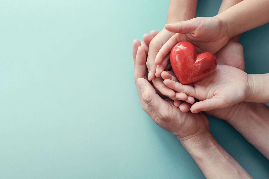 Adult and child hands holding a decorative heart showcasing empathy and care.